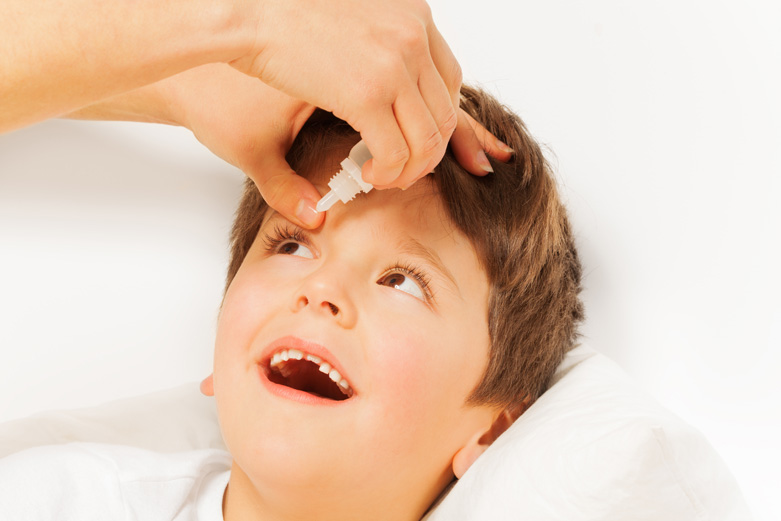 madre ayudando a su hijo aplicar gotas oculares en el ojo